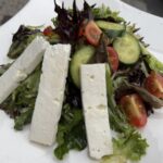 Bleu house salad comes with feta cheese, spring mix, cherry tomatoes, and cucumbers tossed in an asian vinaigrette